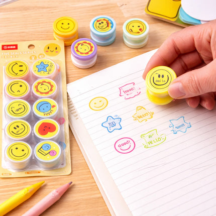 Colorful smiley face stamps on a wooden surface with a hand using one of the stamps.