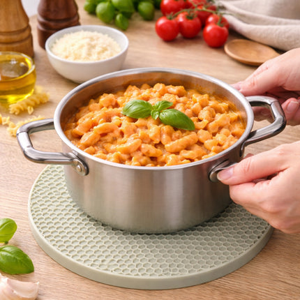 Stainless steel pot with pasta on a wooden table with ingredients