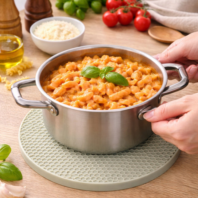 Stainless steel pot with pasta on a wooden table with ingredients