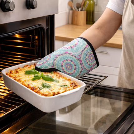 Person removing a dish of lasagna from an oven with a patterned oven mitt.