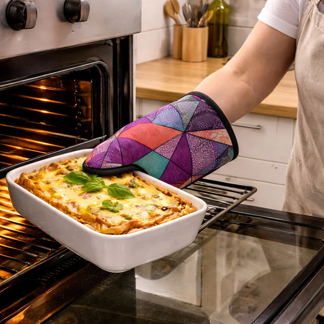 Person removing a dish of lasagna from an oven with a colorful quilted oven mitt.