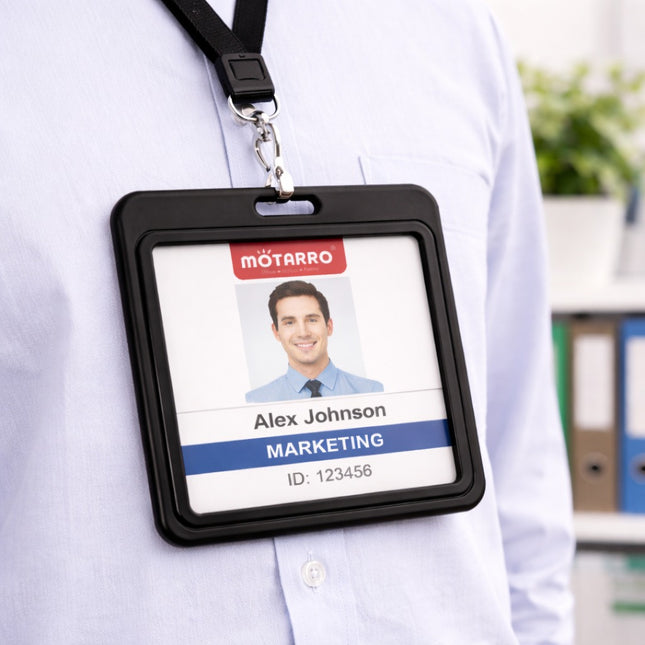 Person wearing a name badge holder with a name badge on a blurred office background