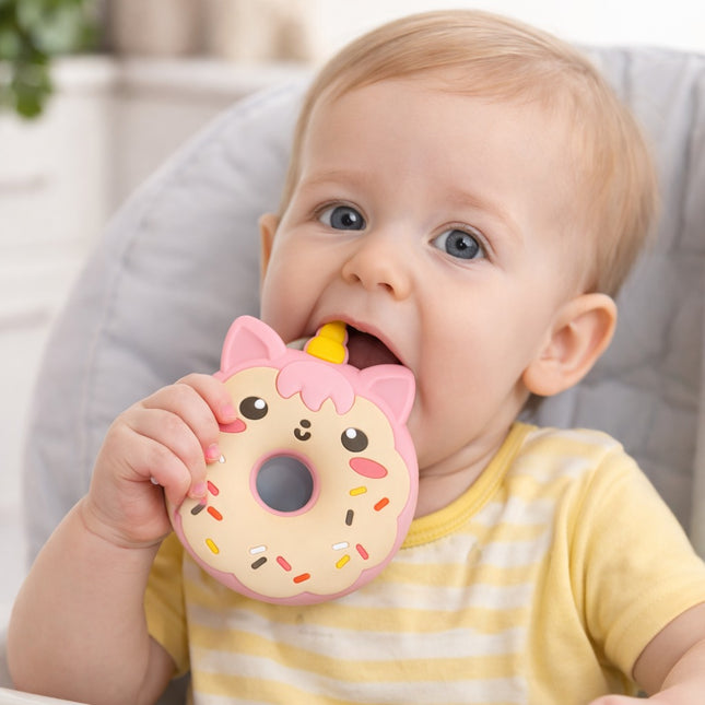 Baby holding a donut-shaped toy with sprinkles and a face