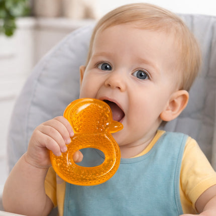Baby holding an orange teething ring with a blurred background