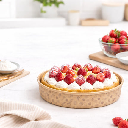 Strawberry tart on a wooden board with a bowl of strawberries in the background.