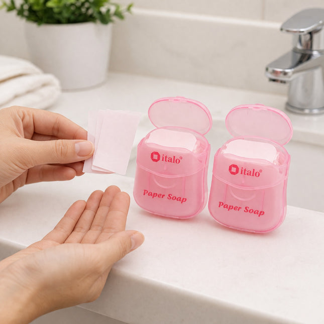 Person using italo paper soap on a bathroom counter with two pink soap dispensers.