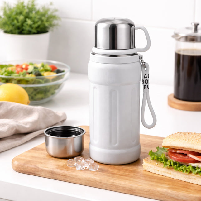 White insulated bottle with silver lid on a kitchen counter with food items.