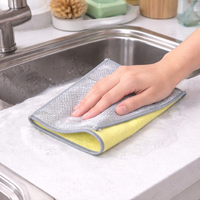 Person cleaning a kitchen sink with a microfiber cloth