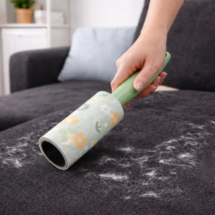Person using a floral-patterned pet hair remover on a sofa with pet hair collected.
