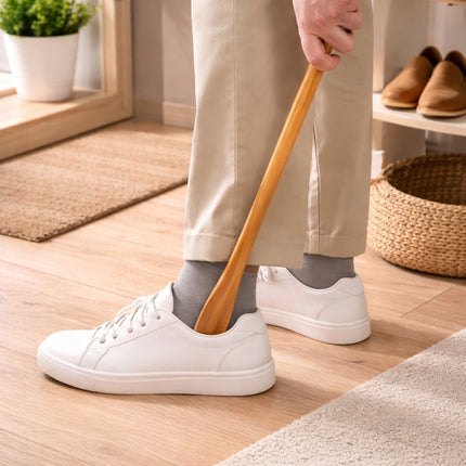 Person wearing white sneakers and beige pants holding a wooden spoon indoors.