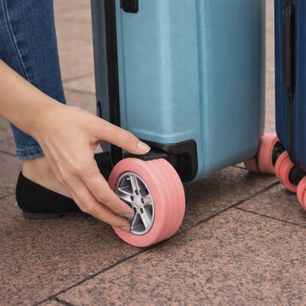 Person adjusting a pink suitcase wheel on a blue suitcase.