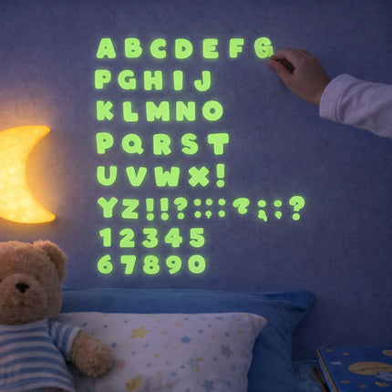 Glowing green alphabet and numbers on a dark blue wall with a teddy bear and moon lamp.
