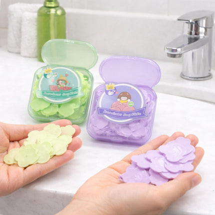Hands holding green and purple soap slices with containers in the background on a sink.