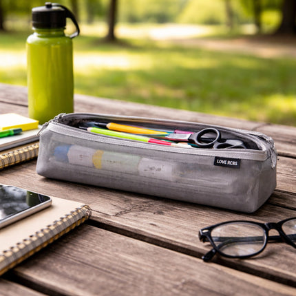 Gray pencil case with stationery items on a wooden table outdoors