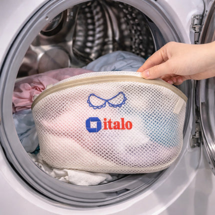 Hand holding a mesh laundry bag with 'italo' branding in front of an open washing machine.