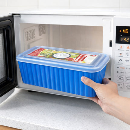 Person holding a blue silicone food container with a lid over an open microwave.