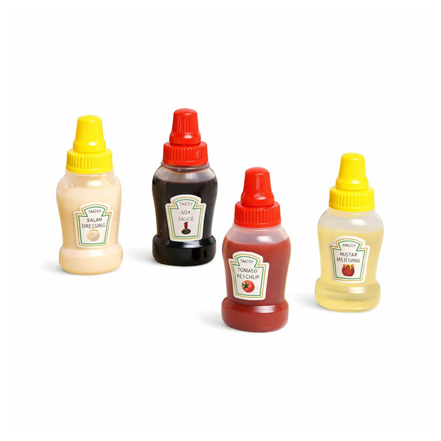 Four miniature condiment bottles with colorful lids on a white background
