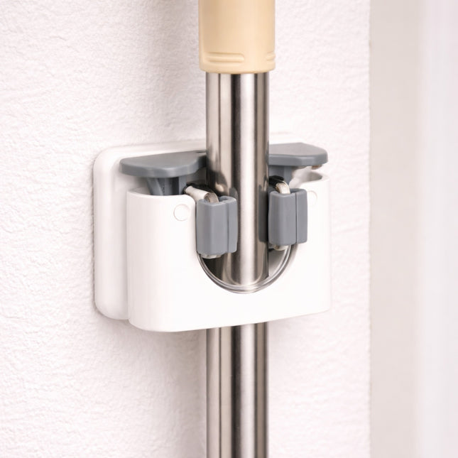 Mop and broom holder attached to a wall with a white background