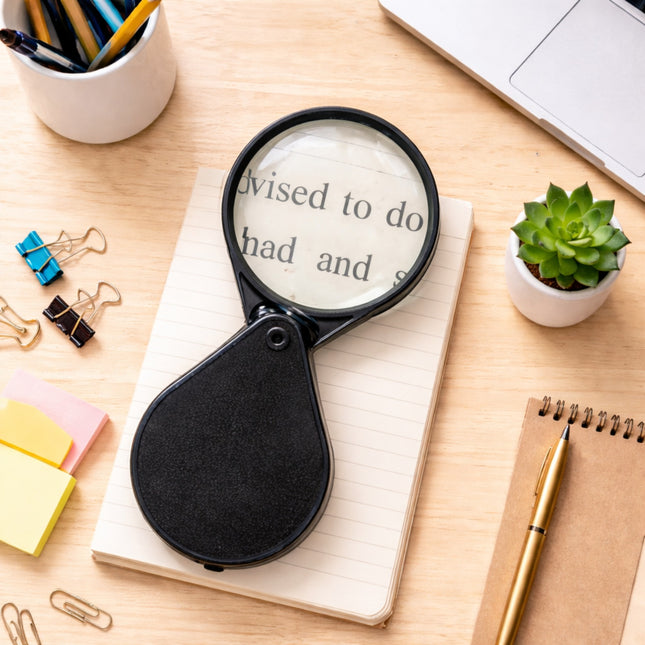 Magnifying glass on a notebook with office supplies on a wooden desk