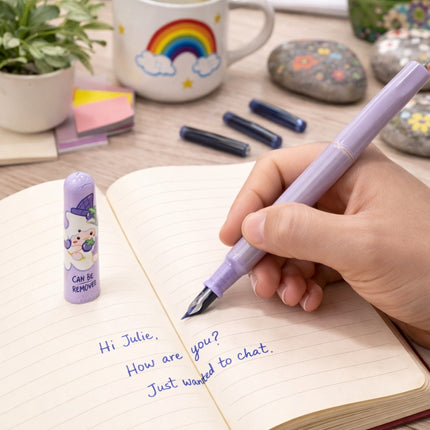 Hand writing in a notebook with a purple pen, surrounded by stationery items on a desk.
