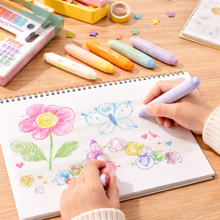 Children's hands coloring a butterfly and flower with pastel markers on a wooden table.
