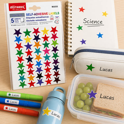 Colorful star labels on a sheet, with a lunch container, water bottle, and pencil case featuring the name 'Lucas'.
