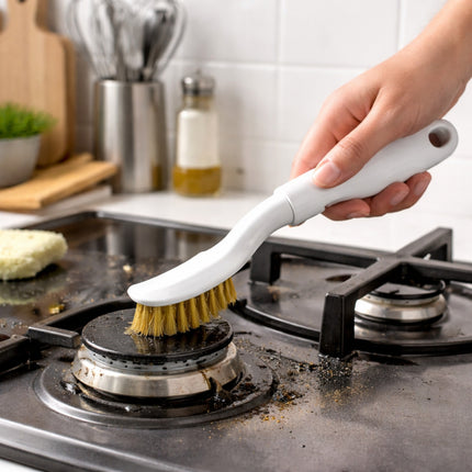 Person cleaning a stove burner with a scrubbing brush