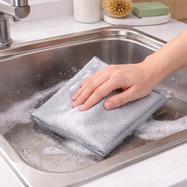 Person cleaning a kitchen sink with a gray scrubber