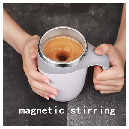 Person holding a white mug with a metallic interior filled with a brown liquid on a dark background, with text 'magnetic stirring'.