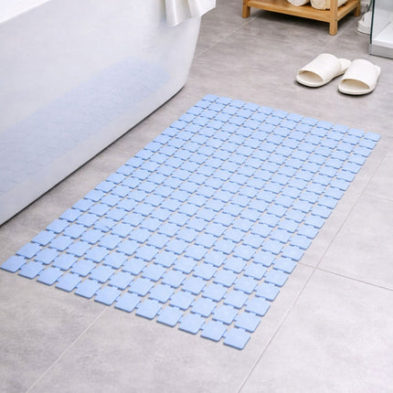 Blue bath mat on a bathroom floor with white slippers nearby