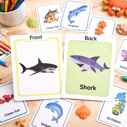 Educational cards with animal illustrations on a wooden surface with stationery items.