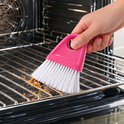 Person cleaning an oven with a pink brush