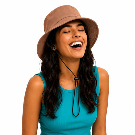 A woman with long dark hair wearing a brown bucket hat with a black chin cord and a teal ribbed tank top, smiling with her eyes closed against a solid white background.