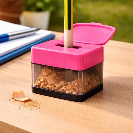 Pink pencil sharpener with a pencil being sharpened on a wooden surface.