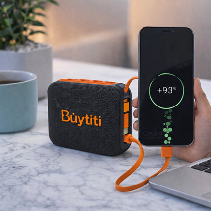 Portable power bank with orange and black design, labeled 'Buytiti', charging a smartphone on a marble surface.