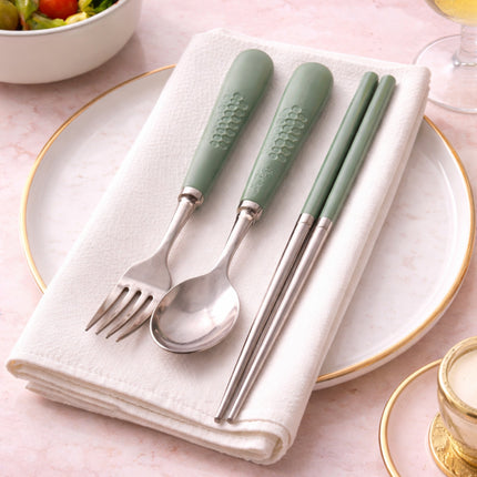 Set of green-handled cutlery on a folded white napkin with a pink background.