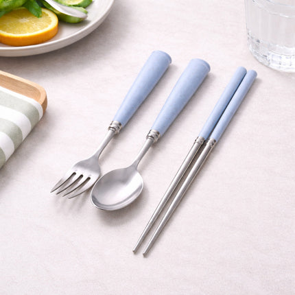 Set of silver cutlery with light blue handles on a neutral surface.
