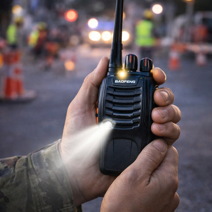 Hand holding a Baofeng walkie-talkie with a blurred background of people and traffic lights.