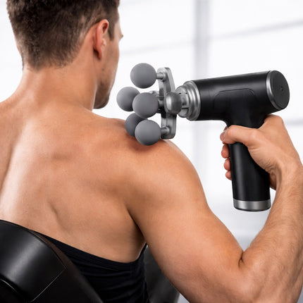 Person using a handheld massage gun on their shoulder against a white background