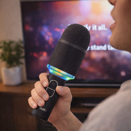 Person holding a microphone with colorful light effects in front of a television screen displaying a karaoke interface.