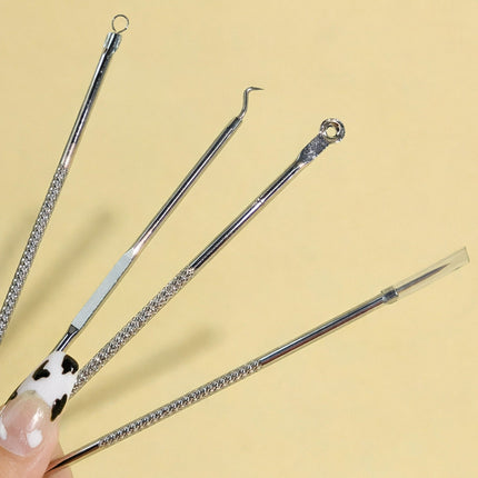 Set of four silver skincare tools held by a hand on a beige background