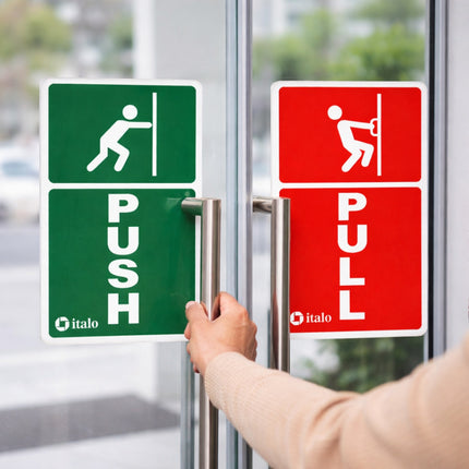 Push and pull signs on a glass door with a hand reaching to open it.