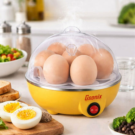 Yellow egg cooker with eggs on a kitchen counter, surrounded by food items.