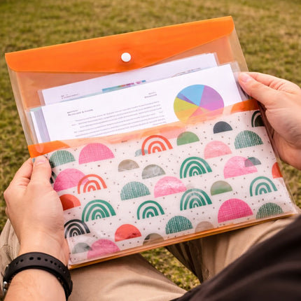 Person holding a folder with colorful rainbow pattern on a grassy background