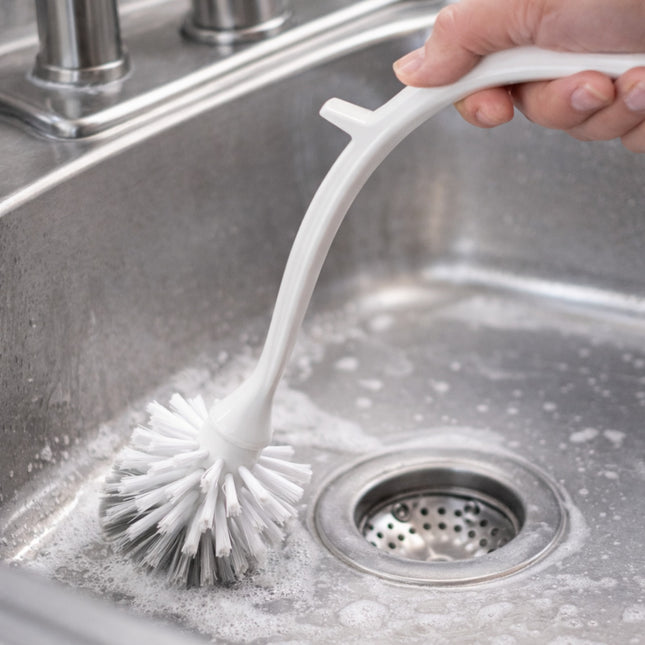 Person cleaning a kitchen sink with a scrubbing brush