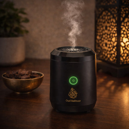 Black oud bakhoor burner with smoke on a wooden surface, surrounded by decorative items.