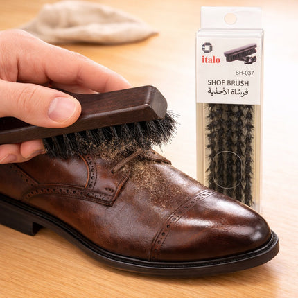 Person cleaning a brown leather shoe with a brush, next to italo shoe brush packaging.