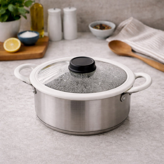 Stainless steel pot with a glass lid on a kitchen counter