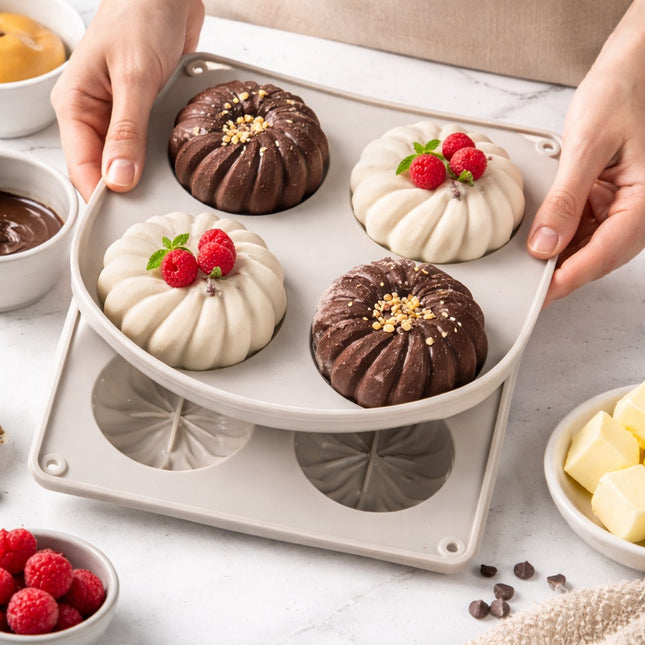 Baked goods in a silicone mold with hands holding it, surrounded by ingredients on a marble surface.