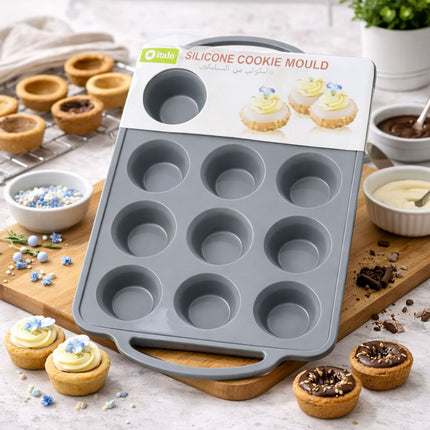 Silicone cookie mould on a wooden board with baked cookies and ingredients in the background